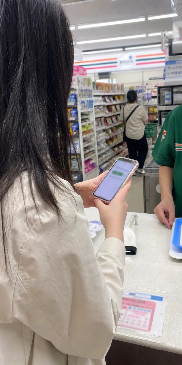 일본 편의점 계산대에서 스마트폰으로 QR 결제를 진행하는 여행자